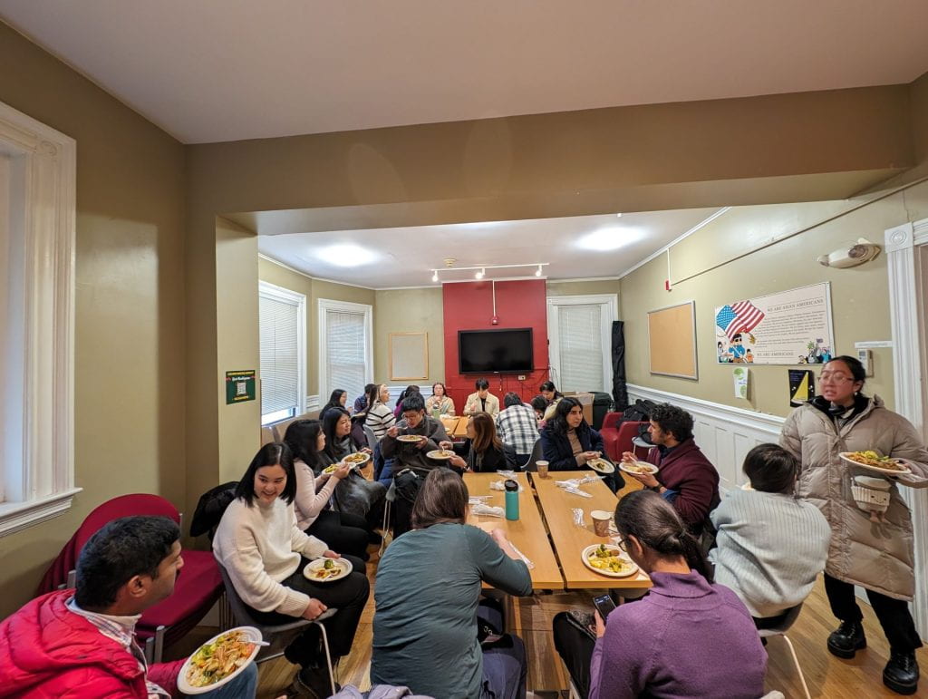 Asian faculty and staff enjoy food and conversation during a gathering.
